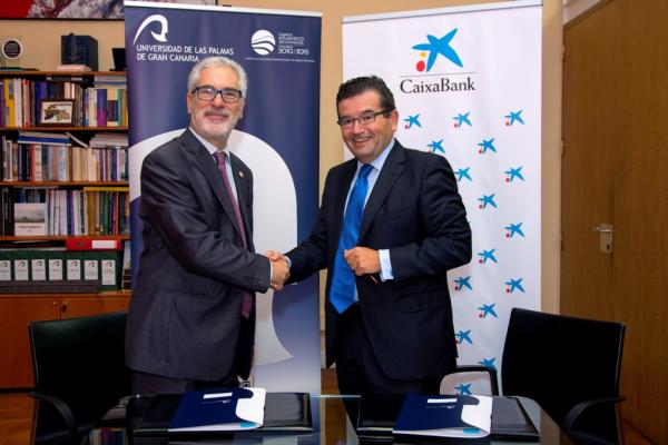 El Rector (i) y el Director Territorial de CaixaBank en Canarias estrechan las manos tras la firma